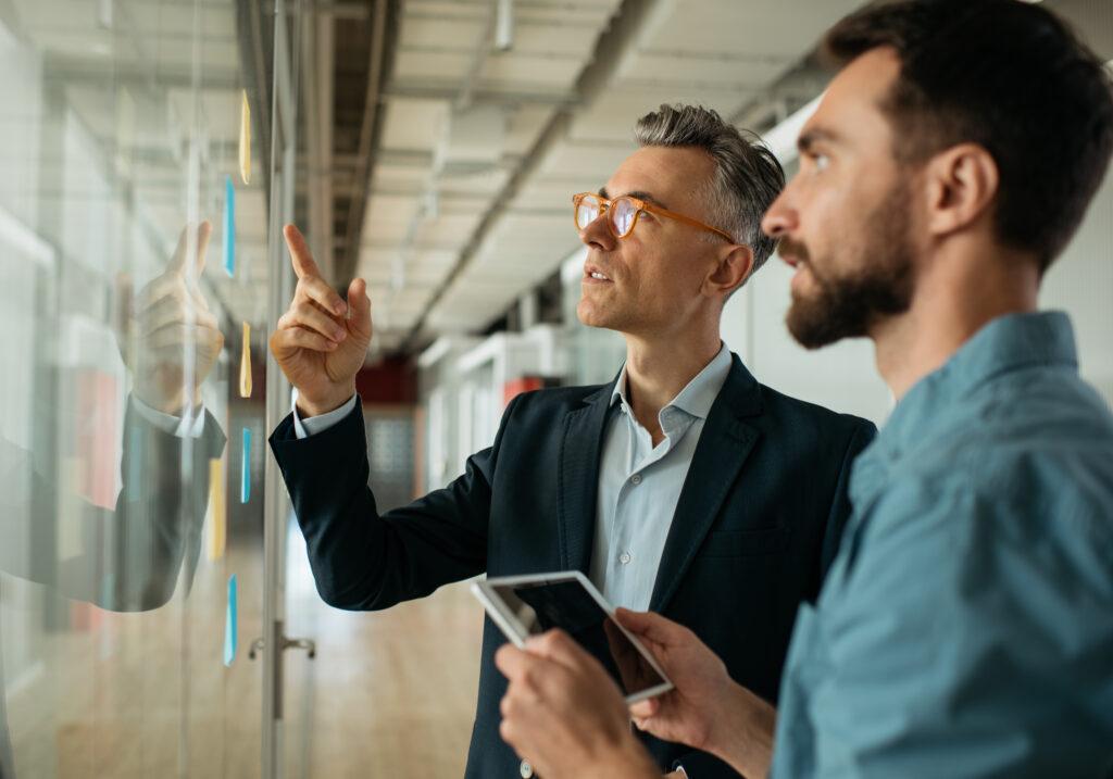 8-scrum-master-using-sticky-notes-standing-near-planning-board-office